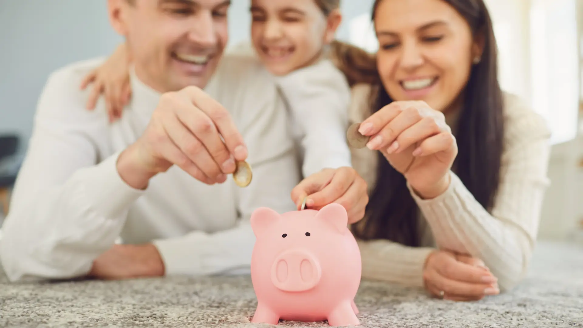 Parents and their daughter happily saving money by putting coins into a piggy bank, symbolizing financial literacy and savings thanks to solar incentives.